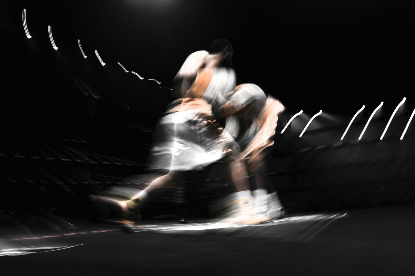 Two athletes locked in a fast, contested moment, motion-blurred under arena lighting.